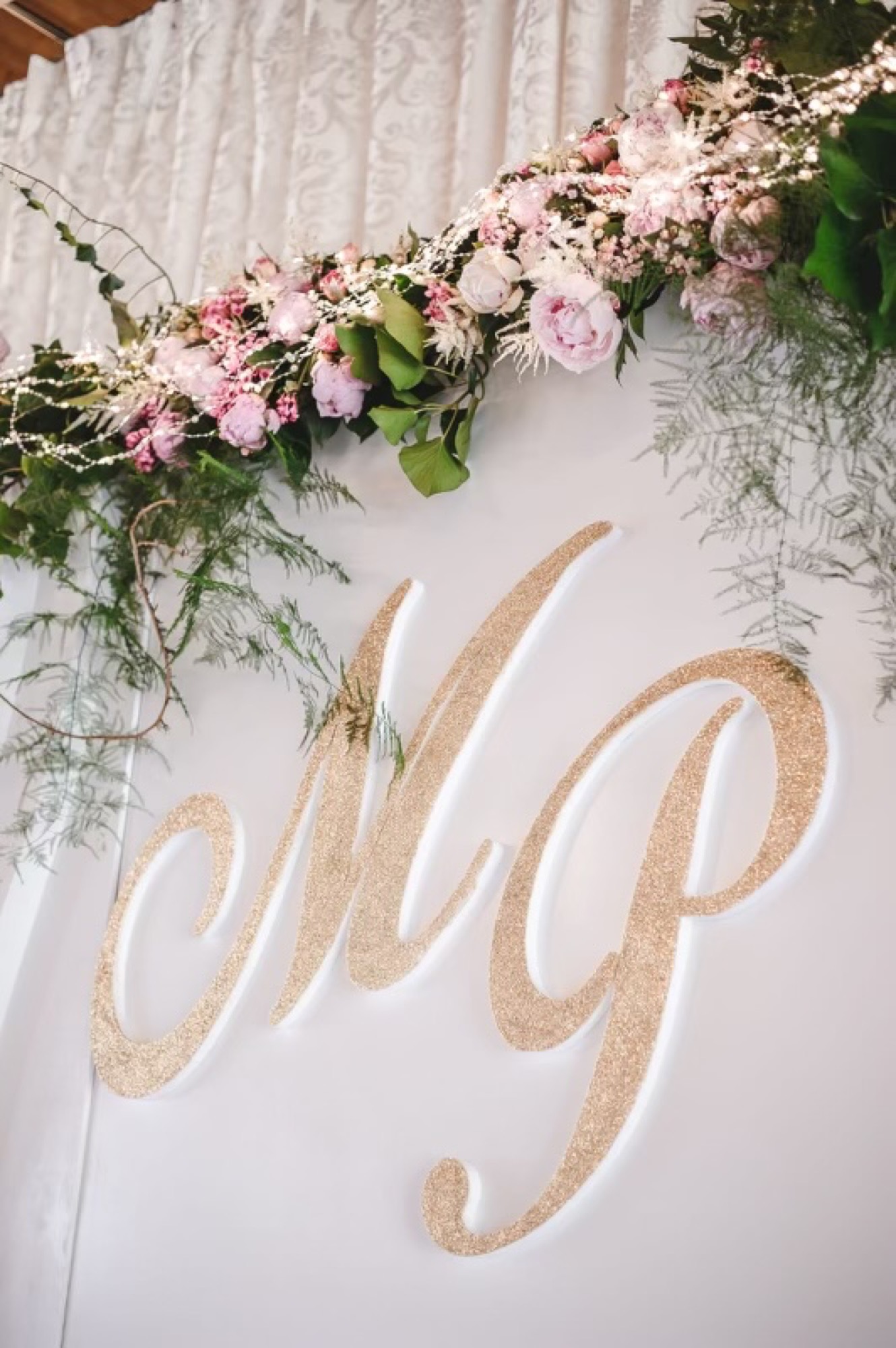 Monogram młodej pary na tle girlandy z piwonii
